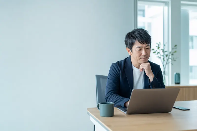経営者がノートパソコンの画面を見ながら、自社がどう紹介されているかを確かめている様子